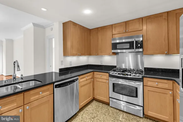 a kitchen with stainless steel appliances granite countertop a stove a sink and a microwave