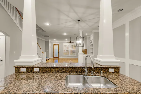 a kitchen with kitchen island granite countertop a sink a stove and a wooden floor