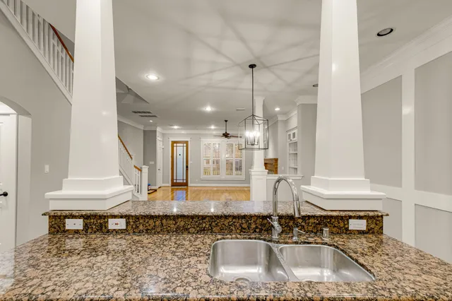 a kitchen with kitchen island granite countertop a sink a stove and a wooden floor