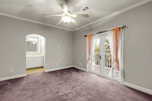 an empty room with chandelier fan and windows