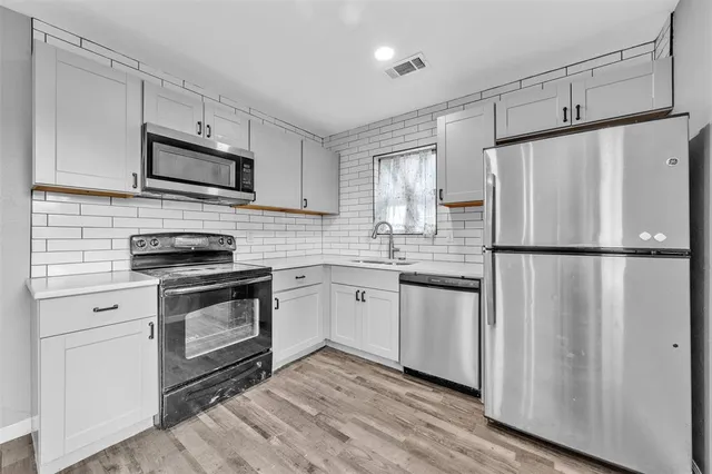 a kitchen with white cabinets stainless steel appliances and sink