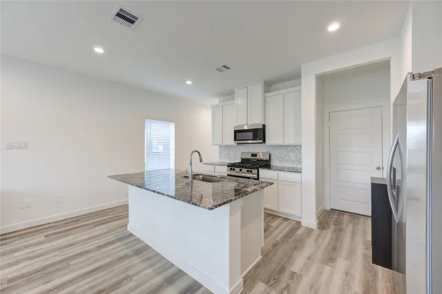 a kitchen with stainless steel appliances granite countertop a sink stove and refrigerator