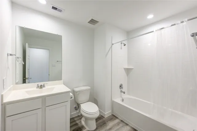 a bathroom with a bathtub shower sink vanity mirror and toilet