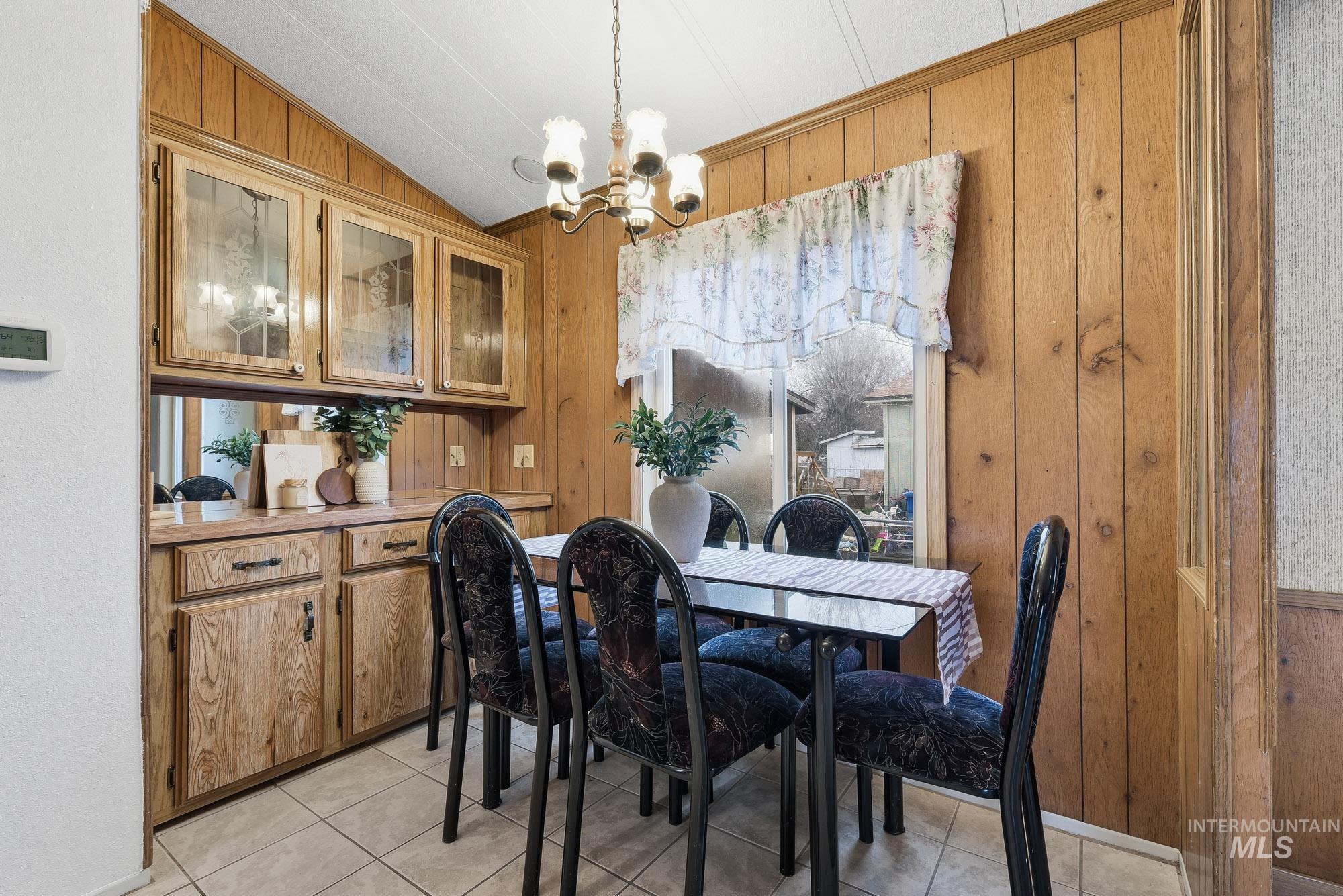 5200 Midway, Unit TRIR 20 Caldwell, ID 83607 - Photo 13 of 31 Dining room with wood walls, a chandelier, lofted ceiling, and light tile patterned floors