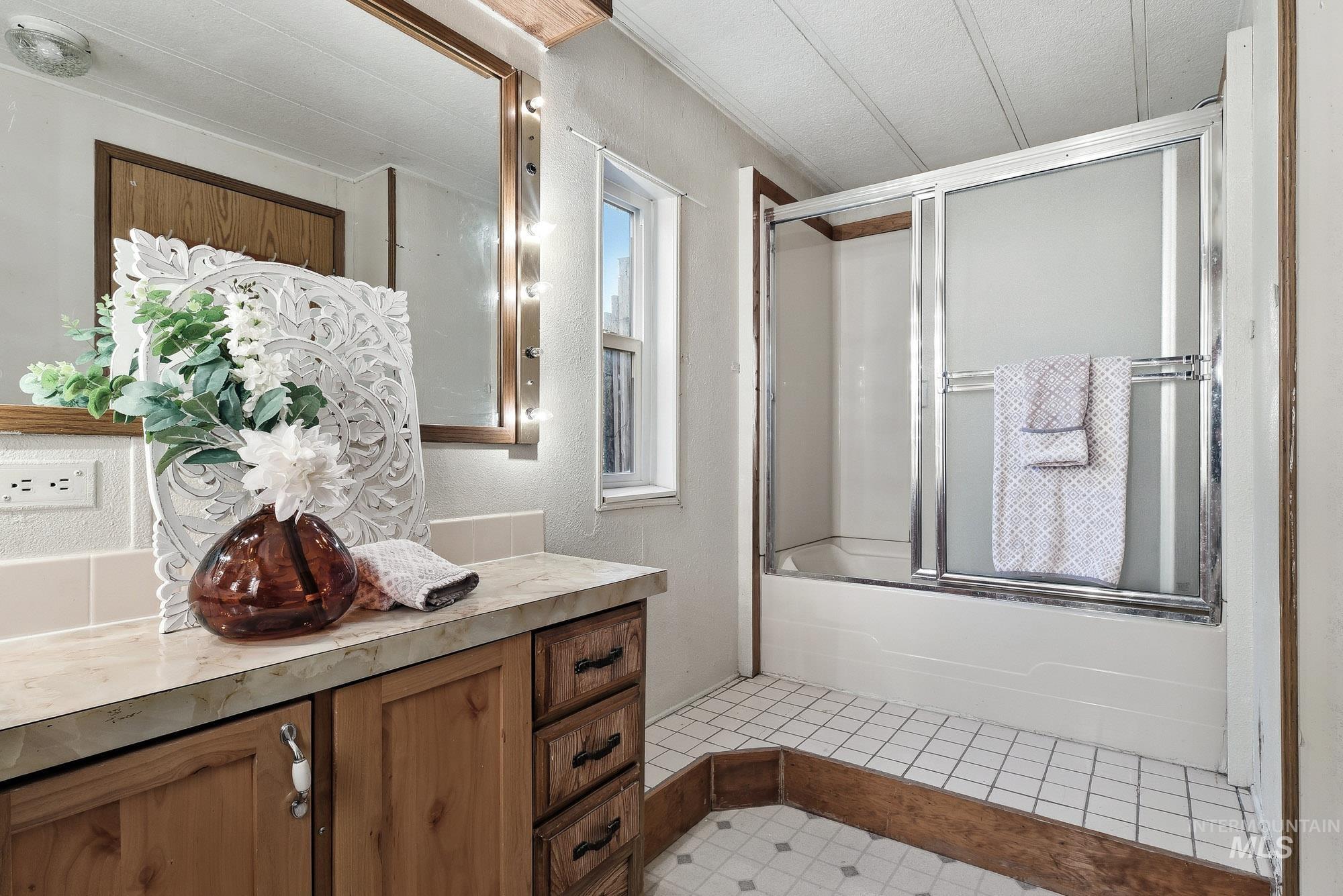 5200 Midway, Unit TRIR 20 Caldwell, ID 83607 - Photo 20 of 31 Full bathroom featuring shower / bath combination with glass door, vanity, and a textured wall