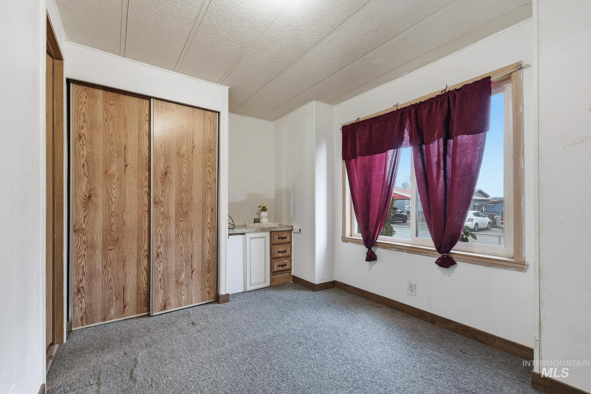 5200 Midway, Unit TRIR 20 Caldwell, ID 83607 - Photo 25 of 31 Bedroom featuring dark carpet, a closet, and a textured ceiling