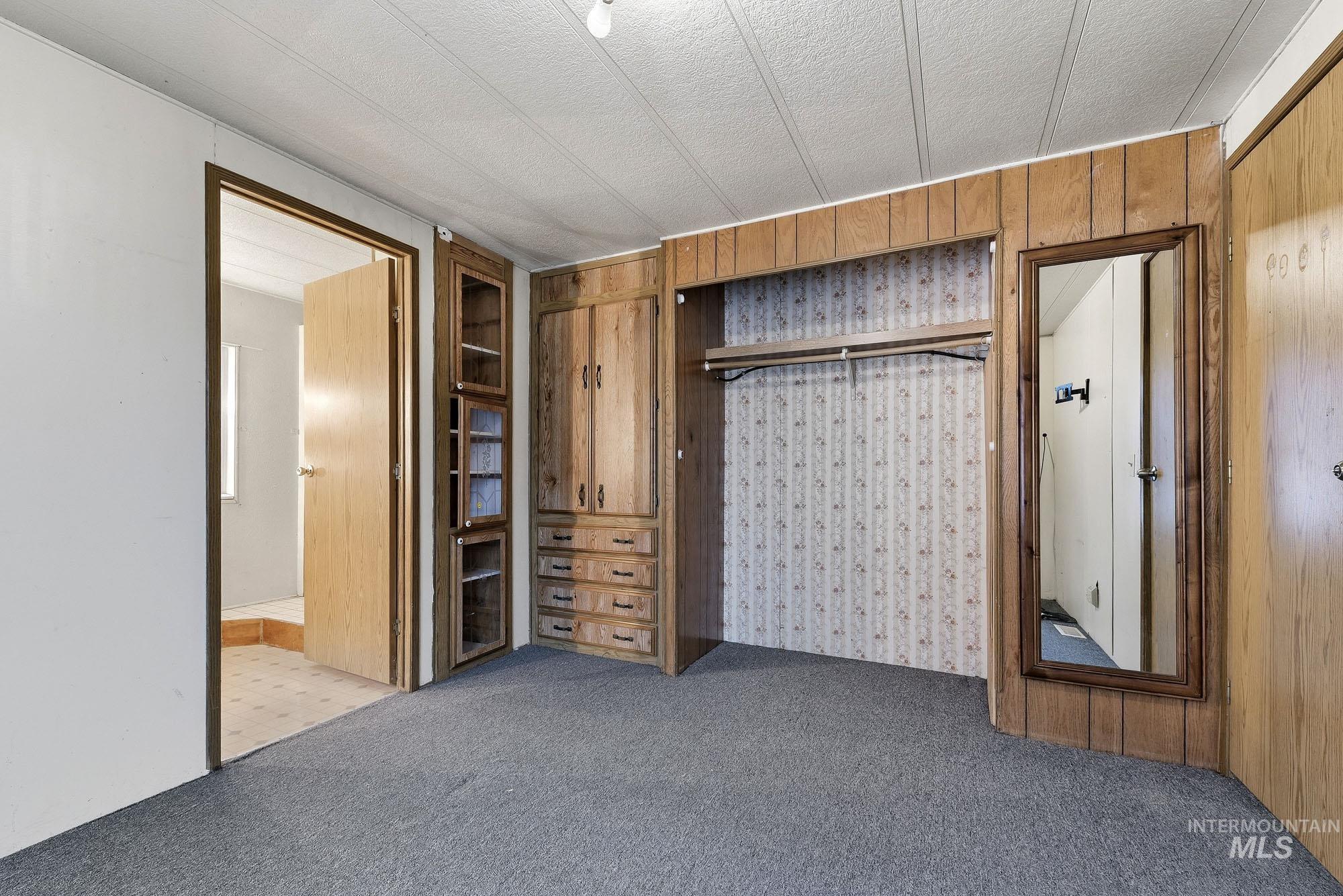 5200 Midway, Unit TRIR 20 Caldwell, ID 83607 - Photo 4 of 31 Unfurnished bedroom featuring carpet flooring, wooden walls, a closet, and a textured ceiling
