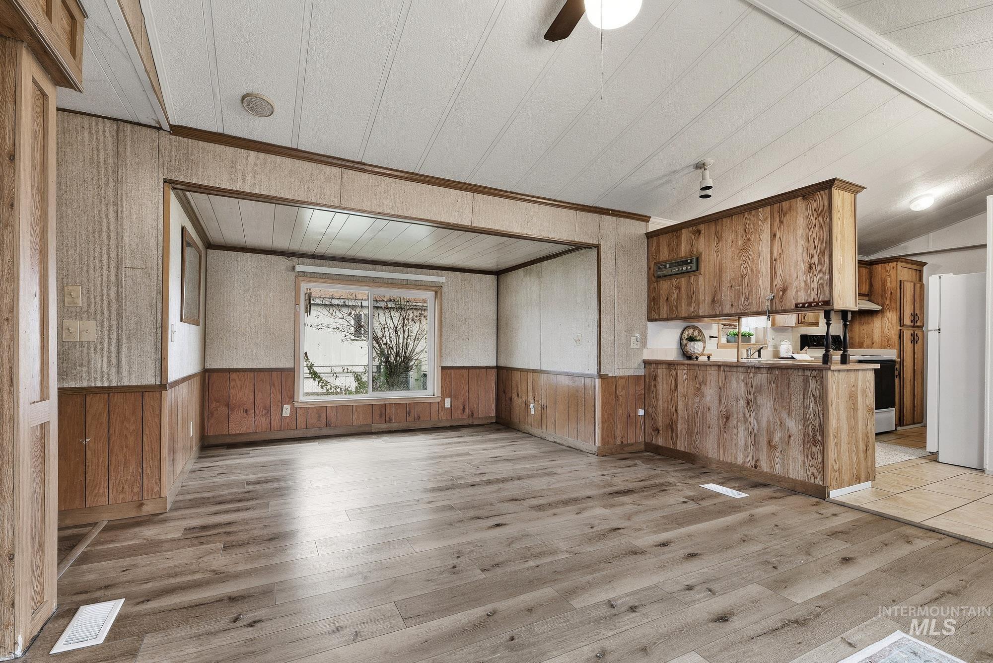 5200 Midway, Unit TRIR 20 Caldwell, ID 83607 - Photo 10 of 31 Unfurnished living room featuring light wood-style flooring, wood walls, wainscoting, and wallpapered walls