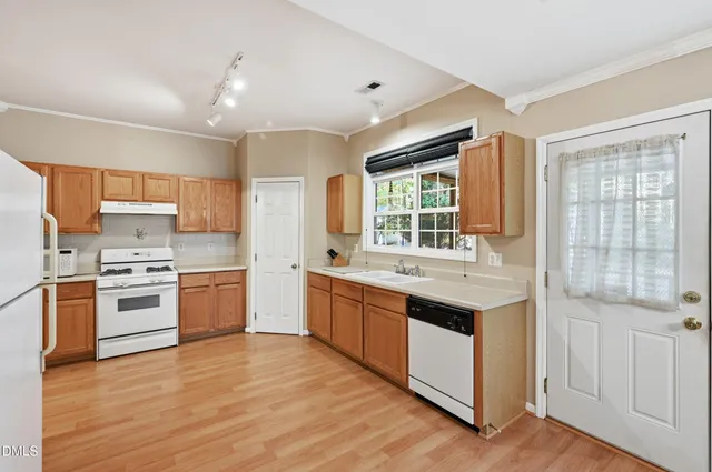 a kitchen with stainless steel appliances kitchen island granite countertop a stove a sink dishwasher a refrigerator and white cabinets with wooden floor