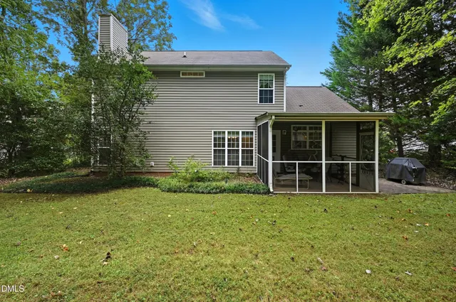 a view of a house with a yard and a large tree