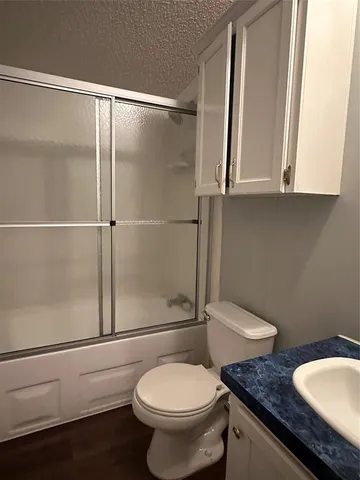 a bathroom with a granite countertop toilet sink and mirror