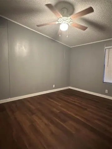 an empty room with wooden floor chandelier fan and windows