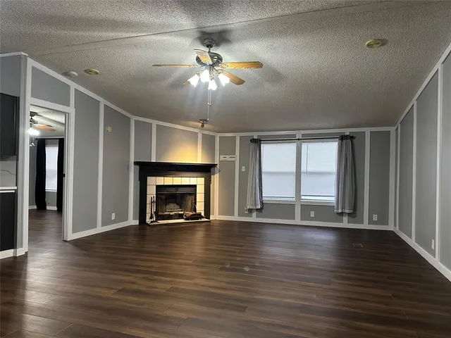 a view of an empty room with wooden floor fireplace and a window
