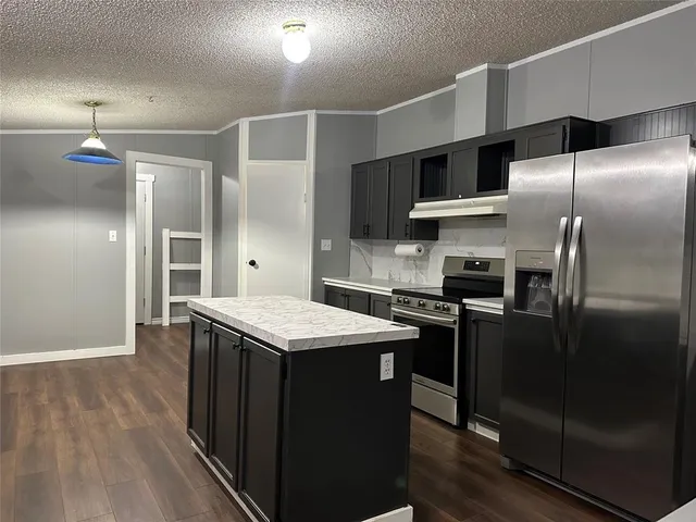 a kitchen with kitchen island a counter space a sink appliances and cabinets