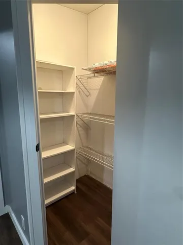 a walk in closet with wooden floor