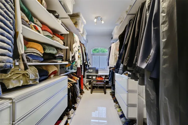 a view of walk in closet with clothes and shoes