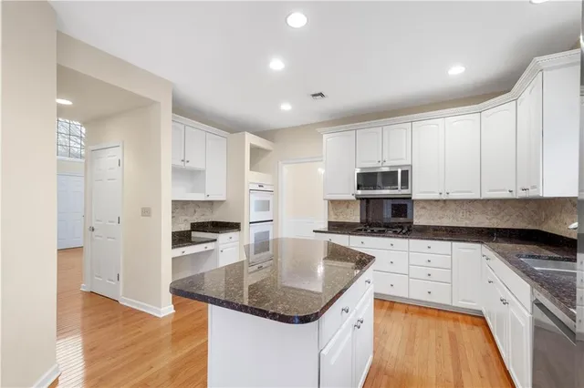 a kitchen with kitchen island granite countertop a sink a counter top space appliances and cabinets