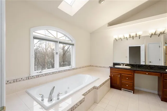 a spacious bathroom with a tub sink and mirror