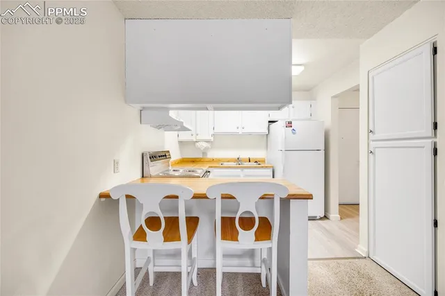 a kitchen with a dining table chairs and refrigerator