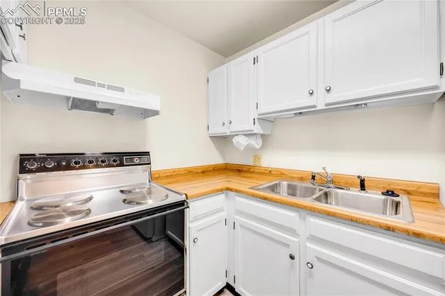 a kitchen with a stove and a white wooden cabinets