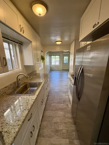 a bathroom with a granite countertop sink a mirror and shower