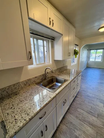 a kitchen with granite countertop a sink a stove and cabinets