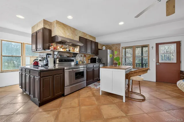 a kitchen with stainless steel appliances granite countertop a stove top oven a sink dishwasher and a refrigerator