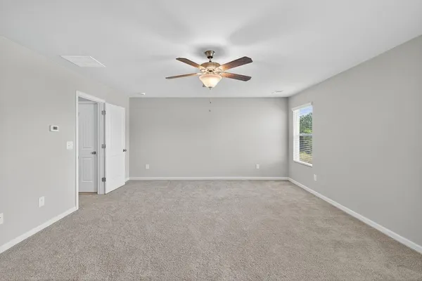 an empty room with windows and chandelier fan