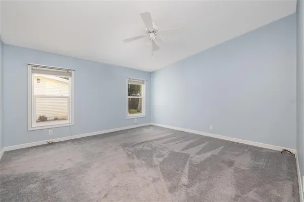 an empty room with a ceiling fan and window