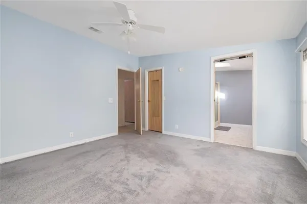 an empty room with closet and a chandelier fan