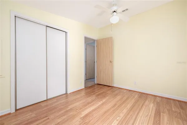 an empty room with wooden floor and fan
