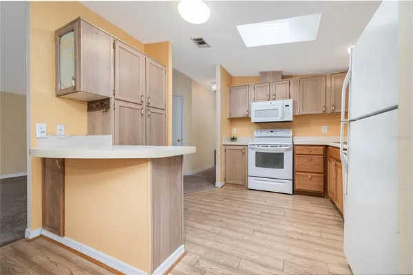 a kitchen with stainless steel appliances cabinets and a wooden floor