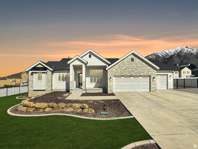 View of front facade featuring a garage, stone siding, concrete driveway, and board and batten siding