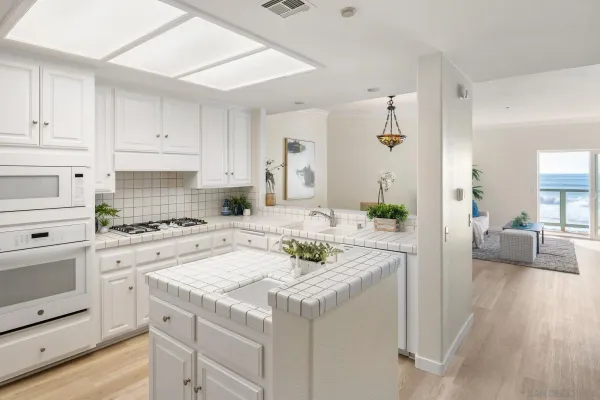 a kitchen with a sink dishwasher and white cabinets with wooden floor