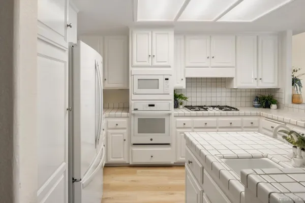 a kitchen with white cabinets and appliances