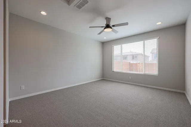 an empty room with closet and a ceiling fan