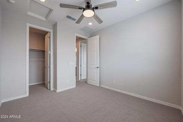 an empty room with closet and a chandelier fan