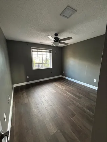 an empty room with windows and ceiling fan
