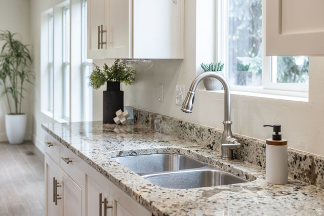 1552 Sumac Drive Logan, UT 84321 - Photo 15 of 72 Kitchen featuring granite countertops, a double basin stainless steel sink, a brushed nickel pull-down faucet, white shaker cabinetry with brushed nickel hardware, and wood-finish flooring