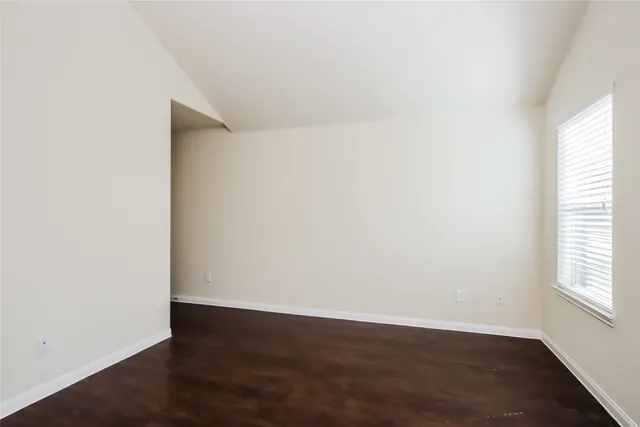a view of an empty room with wooden floor and closet
