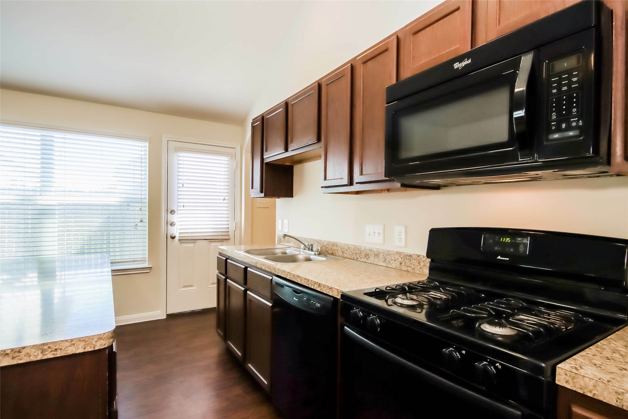 2418 High Island Way, Unit A Houston, TX 77073 - Photo 8 of 14 a kitchen with stainless steel appliances a stove a microwave and wooden cabinets