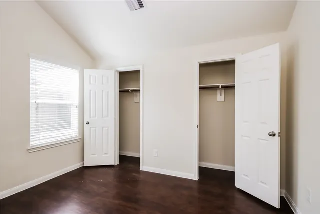 an empty room with wooden floor and window