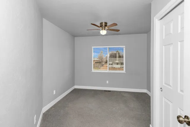 an empty room with a window and ceiling fan