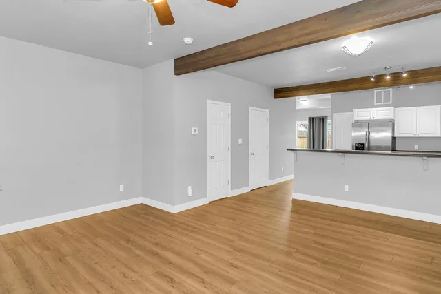 an empty room with wooden floor and windows