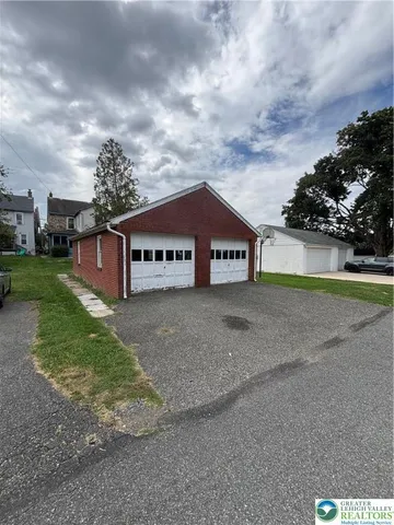 a sign board with a big yard and large trees