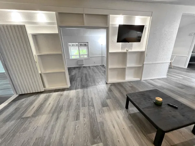 a view of an empty room with wooden floor and window