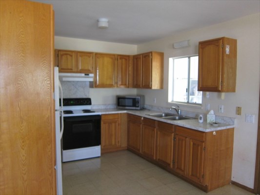 8562 Kekaha Road Kekaha, HI 96752 - Photo 5 of 12 a kitchen with stainless steel appliances granite countertop a sink stove and refrigerator
