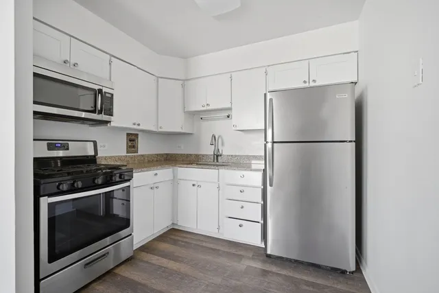 a kitchen with stainless steel appliances white cabinets white stove a microwave and a refrigerator