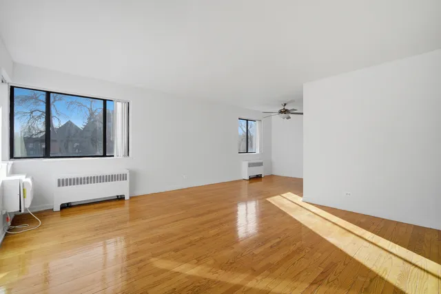 a view of empty room with wooden floor and fan