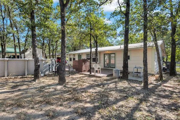 a view of a house with large tree and wooden fence